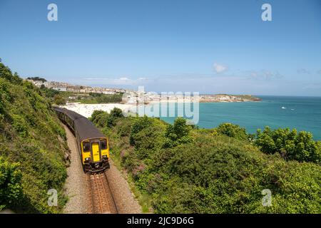 St Ives, Großbritannien. 11.. Juni 2022., Zug fährt von St. ives ,cornwall auf der lokalen Zweiglinie Ein Zug fährt auf der malerischen St. Ives Bay Railway Line, die durch Lelant Beach im Hintergrund führt, auf dem Weg nach St. Ives Quelle: kathleen White/Alamy Live News Stockfoto