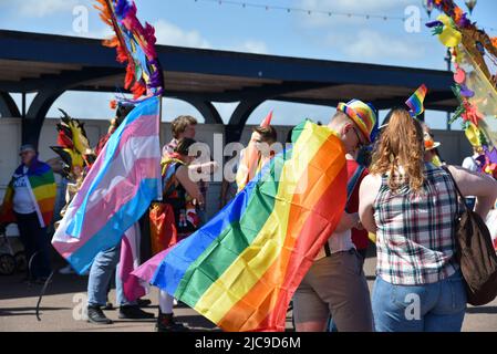 Menschen treffen sich am Startpunkt der Portsmouth Pride 2022 Parade. Helle Regenbogenfarben in der einen oder anderen Form sorgen für einen bunten Tag. Stockfoto