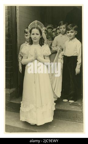 Originalpostkarte aus den 50er Jahren einer jungen May Queen vor der Kirche mit Anwesenden, katholischer Prozession, während das Mädchen einen Rosenkranz trägt, Großbritannien Stockfoto