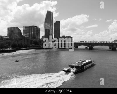 London, Großraum London, England, Juni 08 2022: Monochrom. Uber Boot auf der Themse mit Blackfriars Bridge dahinter. Stockfoto