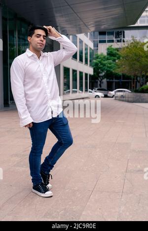 Ganzkörperportrait eines jungen hispanischen oder lateinamerikanischen Mannes am Eingang eines Gebäudes. Modernes Urbanes Konzept. Stockfoto