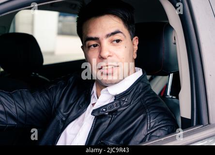 Junger erfolgreicher Latino-Typ fährt sein Auto. Erfolgskonzept. Stockfoto