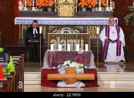 Garmisch Partenkirchen, Deutschland. 11.. Juni 2022. Kardinal Reinhard Marx (r) und Christian Kopp, Landesbischof des Evangelisch-Lutherischen Kirchenbezirks München und Oberbayern, Sitzen Sie während eines Trauergottesdienstes für die Opfer des Eisenbahnunfalls mit fünf Toten und vielen Verletzten in der Pfarrkirche Maria Himmelfahrt vor fünf Kerzen und einem Kreuz. Quelle: Karl-Josef Hildenbrand/dpa-Pool/dpa/Alamy Live News Stockfoto