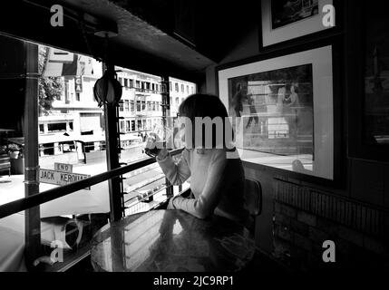 Eine Frau genießt ein Pint Bier im Vesuvio Cafe, einer bekannten Bar in San Francisco, Kalifornien, die von Mitgliedern der Beat Generation 1950s besucht wird. Stockfoto