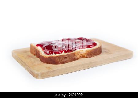 Ein Stück Weißbrot mit Erdbeermarmelade, isoliert auf weißem Hintergrund Stockfoto