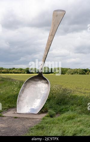 Neben einem Weizenfeld in Cramlington, Northumberland, Großbritannien, könnt ihr die englische Skulptur von Bob Budd, auch bekannt als Giant Spoon, bewundern. Stockfoto