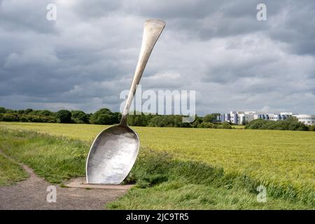 Neben einem Weizenfeld in Cramlington, Northumberland, Großbritannien, könnt ihr die englische Skulptur von Bob Budd, auch bekannt als Giant Spoon, bewundern. Stockfoto