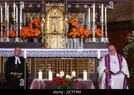 Garmisch Partenkirchen, Deutschland. 11.. Juni 2022. Kardinal Reinhard Marx (r) und Christian Kopp, Landesbischof des Evangelisch-Lutherischen Kirchenbezirks München und Oberbayern, sitzen bei einem Trauergottesdienst für die Opfer des Eisenbahnunfalls mit fünf Toten und vielen Verletzten in der Pfarrkirche Maria Himmelfahrt hinter fünf Kerzen. Quelle: Karl-Josef Hildenbrand/dpa-Pool/dpa/Alamy Live News Stockfoto