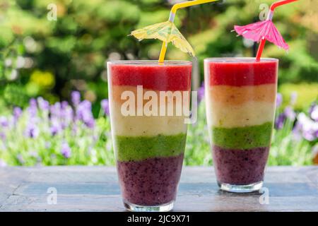 Rainbow leyered Obst Smoothie auf Gartentisch Stockfoto