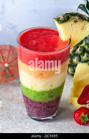 Farbenfroher, leyerierter Frucht-Smoothie mit Regenbogen Stockfoto