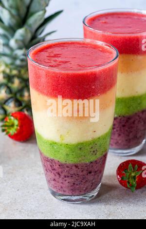 Farbenfroher, leyerierter Frucht-Smoothie mit Regenbogen Stockfoto