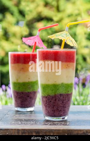 Rainbow leyered Obst Smoothie auf Gartentisch Stockfoto