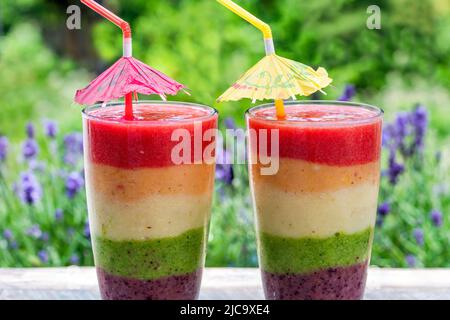 Rainbow leyered Obst Smoothie auf Gartentisch Stockfoto
