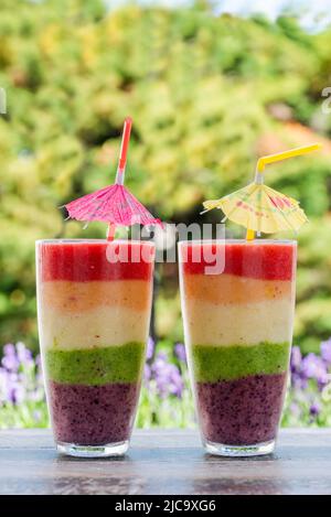 Rainbow leyered Obst Smoothie auf Gartentisch Stockfoto