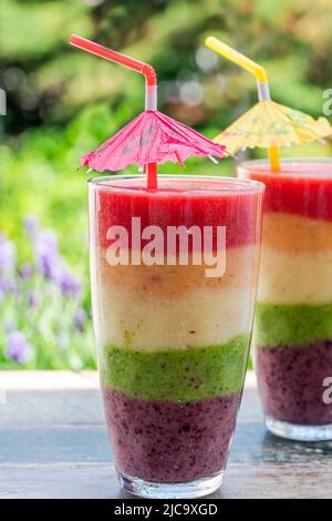 Rainbow leyered Obst Smoothie auf Gartentisch Stockfoto