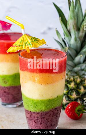 Farbenfroher, leyerierter Frucht-Smoothie mit Regenbogen Stockfoto