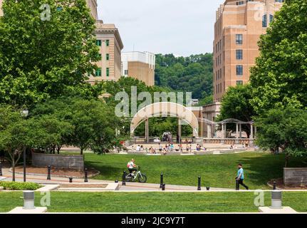 ASHEVILLE, NC, USA-5 JUNE 2022: Sommeransicht des Amphitheaters Pack Square, Menschen, Kinder, die im Wasser spielen, Jongleure auf der Bühne, Frau auf dem Fahrrad. Stockfoto