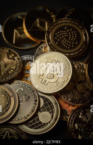 Nahaufnahme eines goldenen Bitcoins in einem Stapel, unter anderem verschiedener digitaler Kryptowährungen. Stockfoto