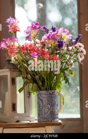 Blauer Krug mit bunten Sommerblumen Stockfoto