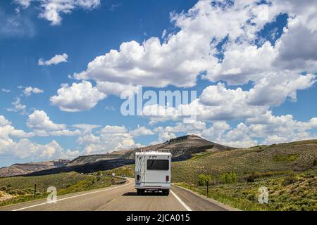 Weißes Camper fährt auf zweispuriger Autobahn mit niedrigen südlichen Colorado Bergen und Buschland im Hintergrund Stockfoto