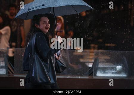 Zwei Frauen schützen sich während eines Regenfalls unter einem Regenschirm. In Ankara, der Hauptstadt der Türkei, fallen heftige Regenfälle. Stockfoto