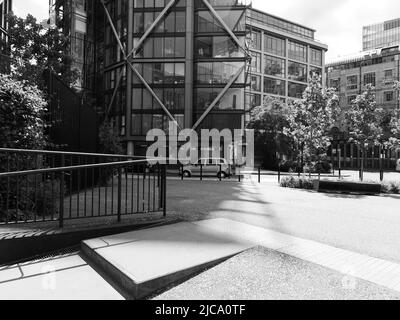 London, Großraum London, England, Juni 08 2022: Monochrom. Das Taxi parkte vor einem modernen Bürogebäude. Stockfoto