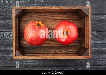 Granatapfel in einer Schachtel auf Holzhintergrund Draufsicht Stockfoto