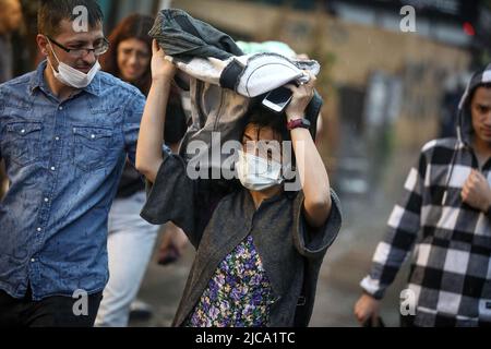 Ankara, Türkei. 11.. Juni 2022. Eine Frau schützt sich vor Regen unter einem Mantel. In Ankara, der Hauptstadt der Türkei, fallen heftige Regenfälle. (Bild: © Tunahan Turhan/SOPA Images via ZUMA Press Wire) Stockfoto