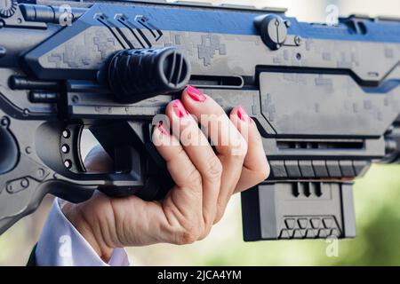 Frau mit roten Nägeln hält ein Spielzeuggewehr in Rio de Janeiro. Stockfoto