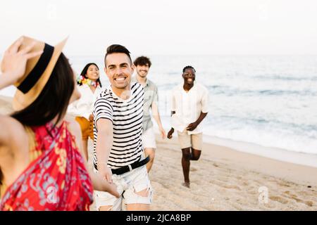 Eine Gruppe junger Freunde, die am Strand laufen Stockfoto