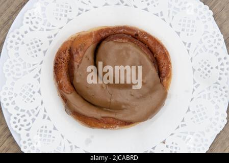 Blick von oben auf verführerische frisch aus dem Ofen Zimtrollen Ahorndonut aus der Bäckerei auf einem Teller serviert. Stockfoto