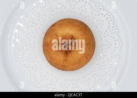 Blick von oben auf verführerischen frischen aus dem Ofen schlichten Donut aus der Bäckerei auf einem Teller serviert. Stockfoto