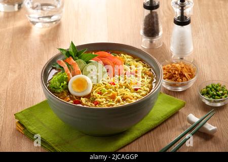 Eine Schüssel gekochte Nudeln mit Garnelen, gekochtem Ei, Tomaten, Gemüse und ​​chili und gebratener Zwiebel Stockfoto