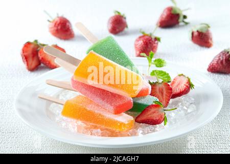 Traditionelles Eis in verschiedenen Farben und Geschmacksrichtungen, serviert auf einem Teller mit Minzblättern und Erdbeeren Stockfoto
