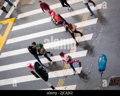 Medellin, Antioquia, Kolumbien - 6 2022. März: Lateinische Frauen und Männer überqueren an einem bewölkten Tag die Straße Stockfoto