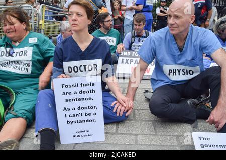 London, Großbritannien. 11.. Juni 2022. Während der Demonstration vor der Downing Street sitzen die Demonstranten mit zusammengeklebten Händen. Ärzte, Krankenschwestern und andere Gesundheitsfachkräfte des Extinction Rebellion versammelten sich in Westminster zu einem Protest, um ein Ende der Investitionen in fossile Brennstoffe zu fordern. Kredit: SOPA Images Limited/Alamy Live Nachrichten Stockfoto