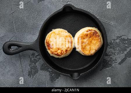 Hüttenkäsepfannkuchen, Syrniki, Ricotta-Krapfen auf gusseiserner Pfanne Pfanne auf gusseiserner Pfanne Pfanne, Blick von oben flach, auf grauem Stein Stockfoto