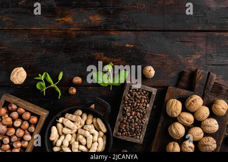 Nüsse in Schalen, Erdnuss, Nussbaum, Pinienkerne und Haselnuss, auf alten dunklen Holztischhintergrund, Draufsicht flach, mit Kopierraum für Text Stockfoto