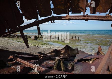 Schiffswrack an der Küste des Atlantischen Ozeans. Rostige Metallreste von Schiffsrumpf an der Meeresküste, die mit Algen bedeckt ist, in der Nähe von Puerto Madryn, Chubut, Patagonien Stockfoto