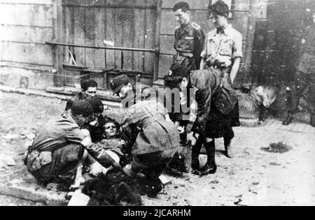 Ein verwundetes Mitglied der polnischen Heimatarmee erhielt während des Warschauer Aufstands erste Hilfe auf der Straße. Der Warschauer Aufstand war ein massiver Versuch der polnischen Heimatarmee, die Wehrmacht und die SS-Besatzung gegen Ende WW2 zu besiegen. Stockfoto