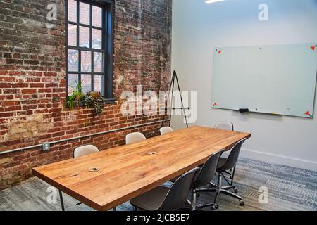 Moderner Büro-Tagungsraum mit Holztisch und Ziegelwand Stockfoto