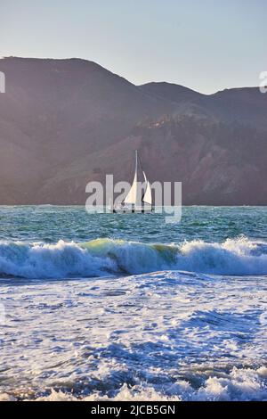Segelboot, das durch die Berge durch die Wellen des Ozeans fährt Stockfoto