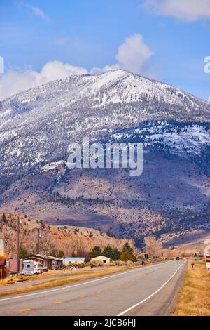 Straße für Touristen, die in Richtung atemberaubender schneebedeckter Berge führen Stockfoto