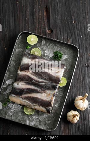 Draufsicht Frozen Wels Filet Lele mit Eis und Limettenscheiben, auf Holztisch. Ausgewählter Fokus Stockfoto