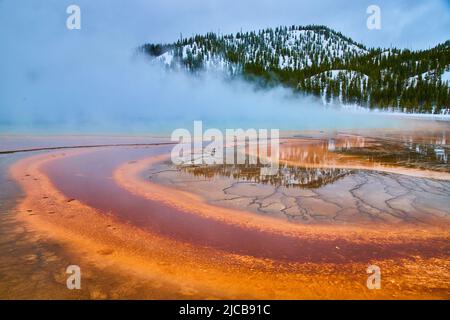 Schichten von rotem und orangefarbenem Wasser aus dem Frühling im Winter in Yellowstone Stockfoto