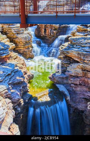 Teil der Brücke über atemberaubende Wasserfälle in Felsen, die in den Abgrund fließen gesehen Stockfoto