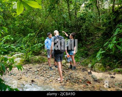 La Estrella, Antioquia, Kolumbien - Februar 13 2022: Gruppe junger Menschen verschiedener Nationalitäten, die mitten in der Natur den Fluss passieren Stockfoto