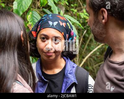 La Estrella, Antioquia, Kolumbien - Februar 13 2022: Braune Frau mit Schmetterlingskopftuch gehört ihren Freunden im Wald zu Stockfoto