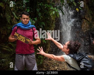 La Estrella, Antioquia, Kolumbien - Februar 13 2022: Junger brauner Mann hält ein Schild mit der Aufschrift „Bitte nicht berühren“ und junge lockige Frau versucht zu berühren Stockfoto