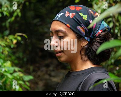 La Estrella, Antioquia, Kolumbien - Februar 13 2022: Braune Frau mit einem Schmetterlingskopftuch geht im Wald spazieren Stockfoto